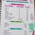 Femme souriante avec un carnet et un stylo en train de créer un budget méthodique.